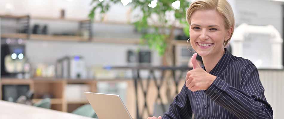 Woman using laptop giving thumbs-up